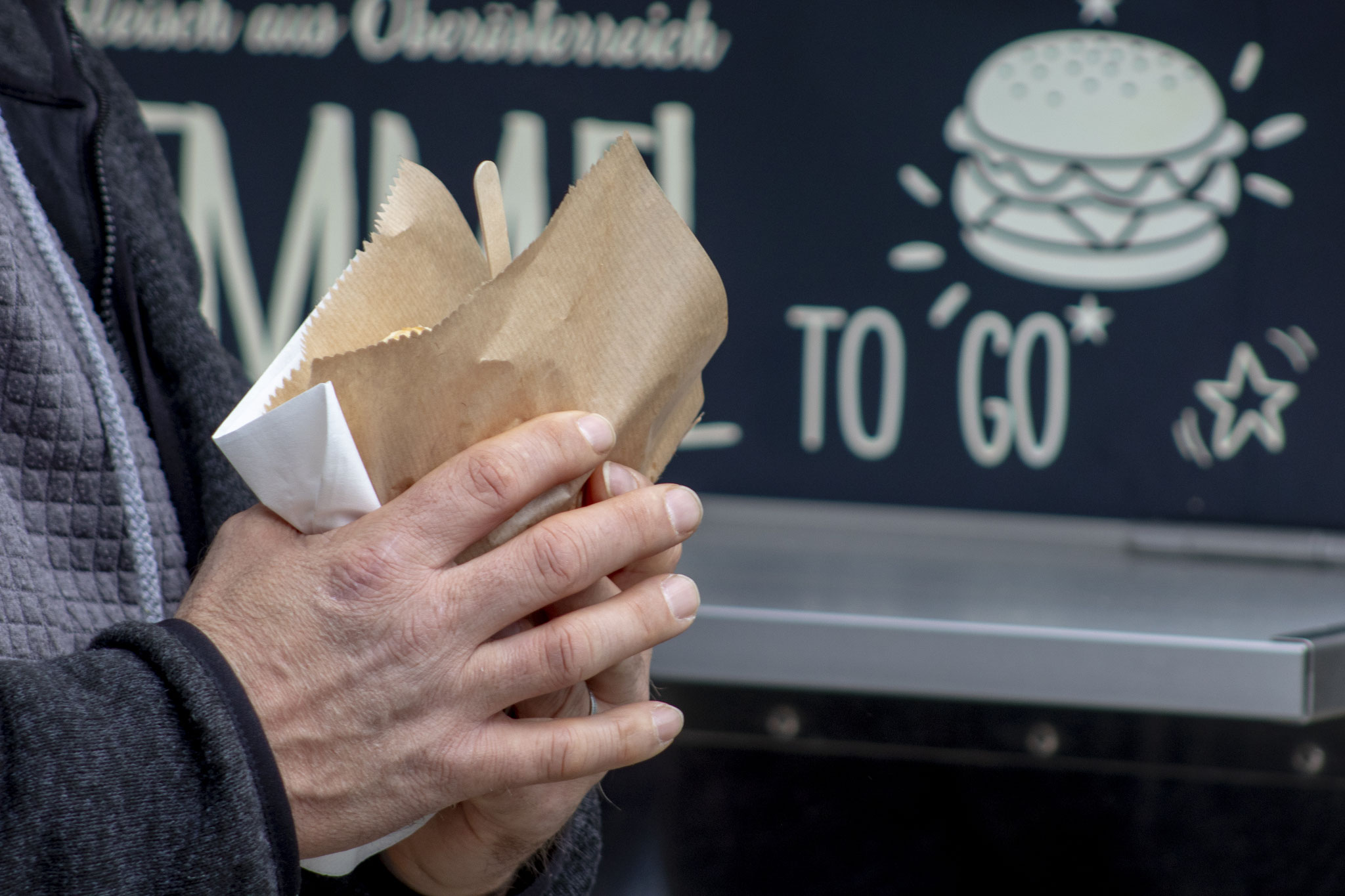 Street-Food-Snack in der Hand vor einem Food Truck